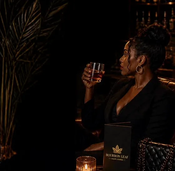A guest with a bourbon in the candlelit lounge